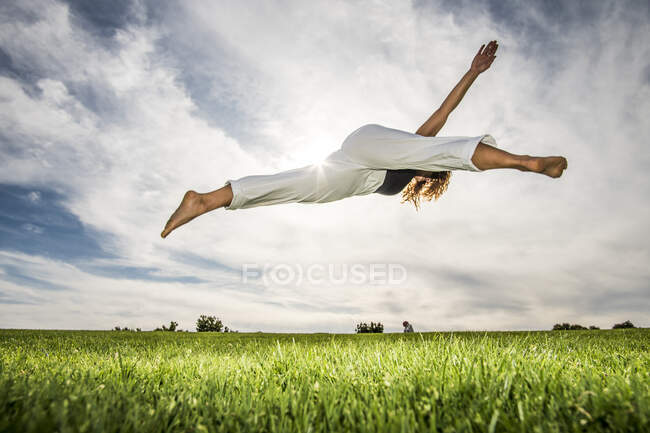 Sportlerin macht Akrobatik im Park bei bewölktem Himmel — Stockfoto