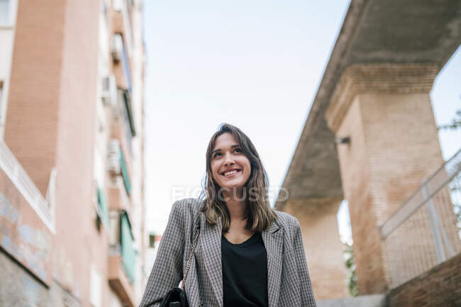 Jeune femme souriante debout contre l'extérieur du bâtiment en ville — Photo de stock