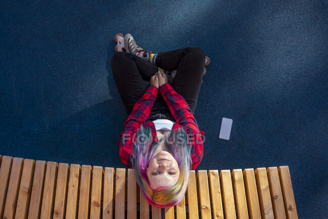 Young woman with dyed hair and roller skates sitting on ground — Stock Photo