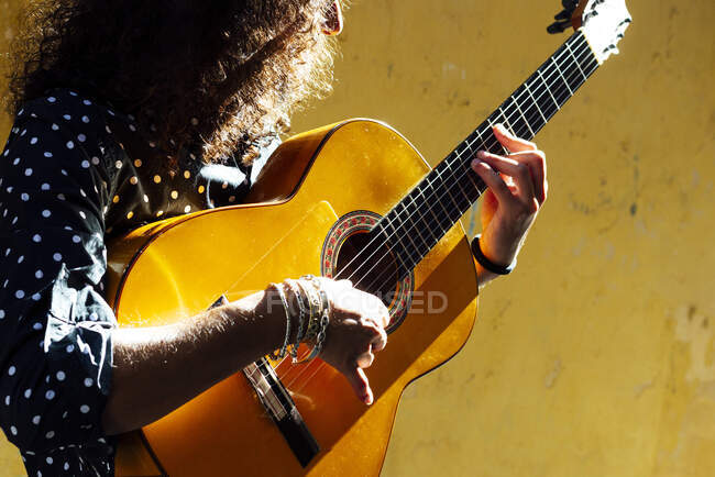 Guitarist playing guitar while standing against yellow wall — Stock Photo
