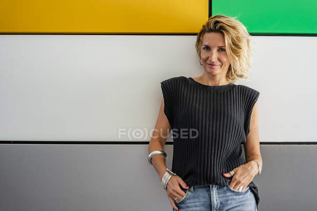 Chef feminino confiante de pé com as mãos nos bolsos contra a parede colorida na escola de culinária — Fotografia de Stock