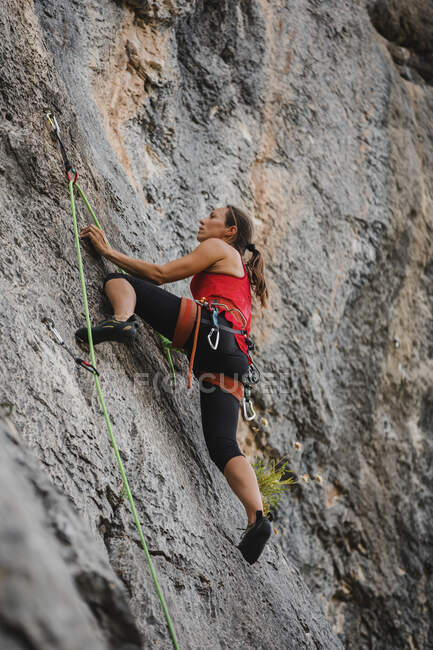 Donna fiduciosa scalare montagna rocciosa con la corda — Foto stock