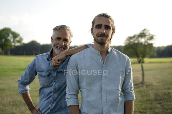 Portrait of happy father with adult son on a meadow in the countryside — Stock Photo