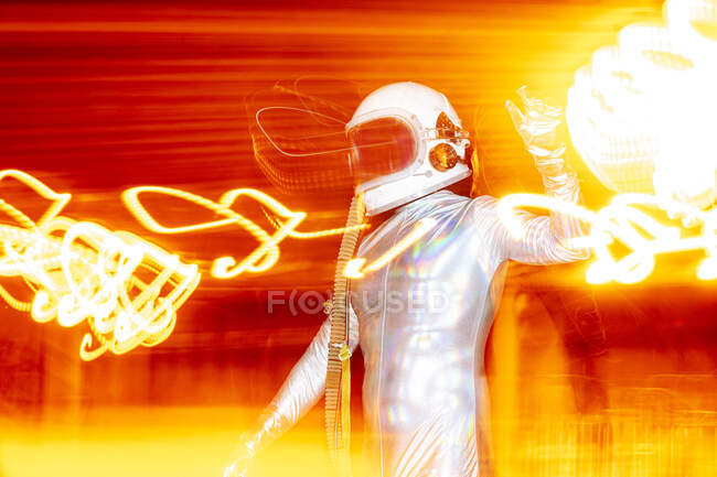 Astronauta masculino con traje espacial de pie en medio de pinturas ligeras - foto de stock