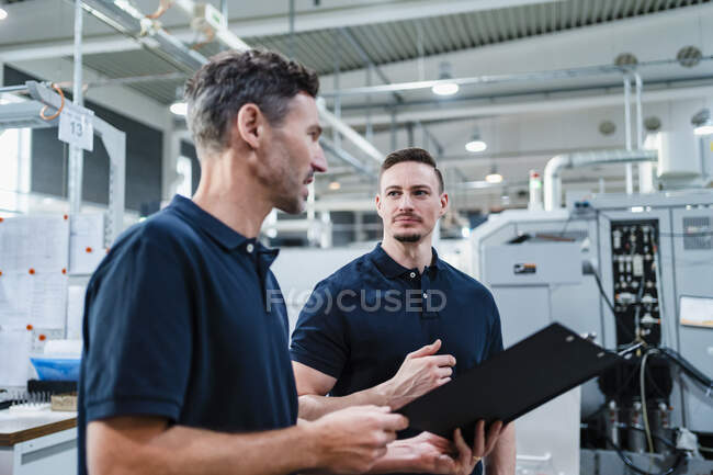 Male engineer looking at coworker while discussing in industry — Stock Photo