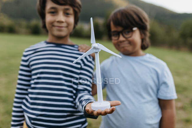 Smiling boys holding windmill toy while standing at backyard — Fotografia de Stock