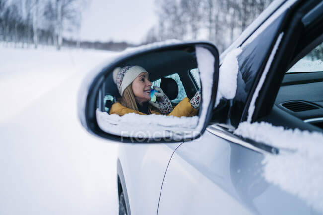 Reife Frau telefoniert im Auto und reflektiert den Seitenspiegel — Stockfoto