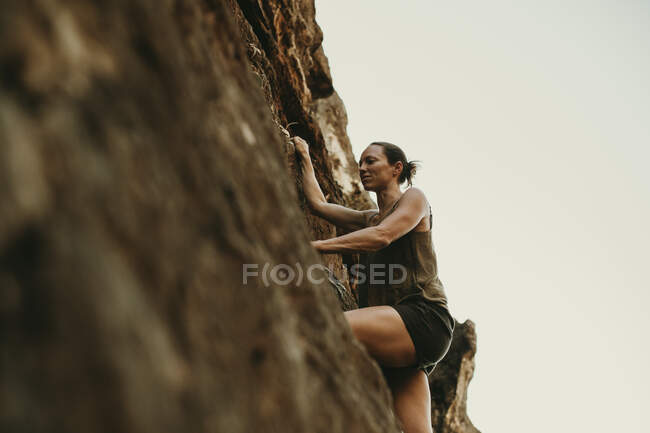 Mujer escalando roca montaña - foto de stock