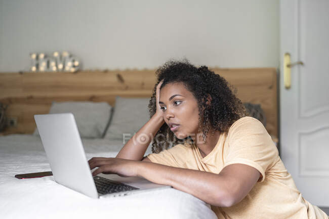 Gestresste junge Frau mit Laptop in der Hand zu Hause im Bett — Stockfoto