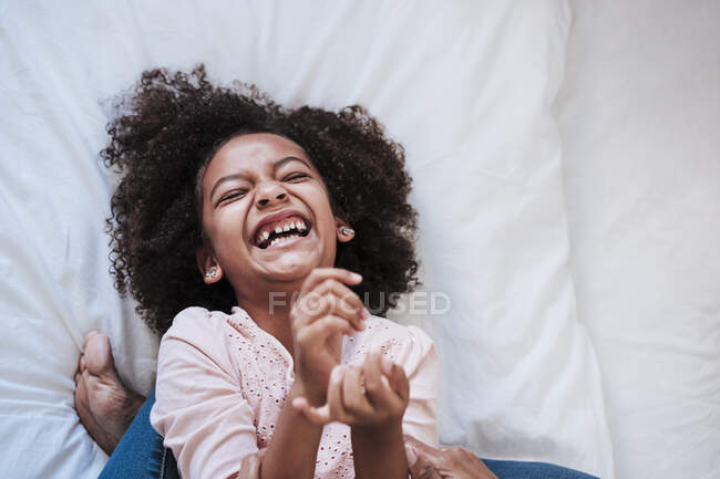 Ragazza carina ridendo mentre sdraiato sul letto a casa — Foto stock