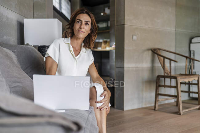 Деловая женщина с помощью ноутбука, сидя на ноутбуке в офисе — стоковое фото