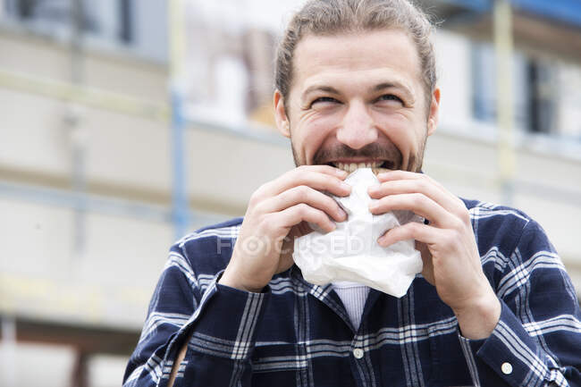 Close-up of construction worker eating bread while sitting at construction site — Stock Photo