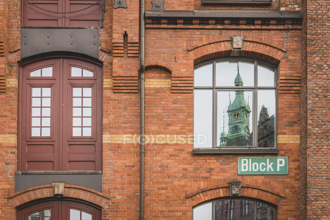 Germany, Hamburg, Speicherstadt, Tower reflected in window of old, brick industrial building — Stock Photo