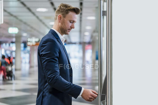 Businessman withdrawing money through card at an ATM — Stock Photo