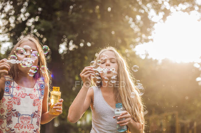 Ragazze che soffiano bolle nel parco durante il tramonto — Foto stock
