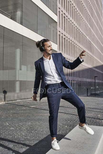Businessman dancing with headphones in city — Photo de stock