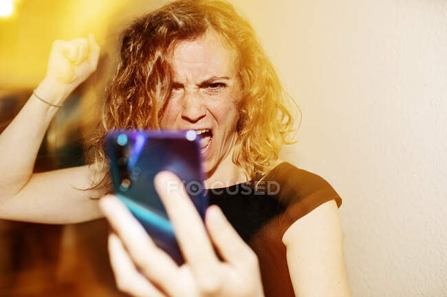 Primer plano de la mujer hablando agresivamente en la videollamada a través del teléfono inteligente en casa - foto de stock