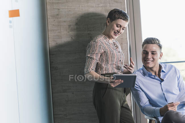 Smiling female entrepreneur discussing over digital tablet with businessman in office — Foto stock