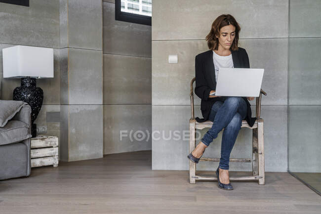Donna d'affari che lavora su computer portatile mentre si siede sulla sedia in ufficio — Foto stock