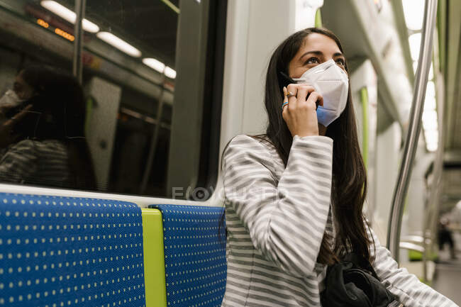 Жінка дивиться геть, розмовляючи по смартфону в поїзді метро — стокове фото