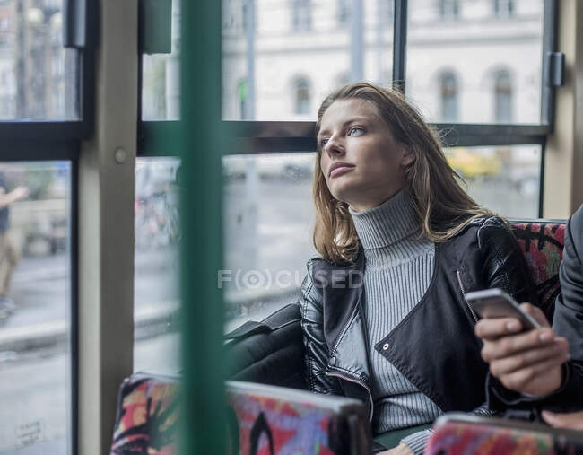 Contemplare giovane donna d'affari seduta dalla mano di un collega maschio che tiene lo smart phone in autobus — Foto stock