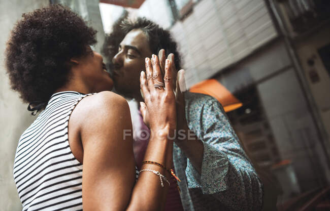 Romantic woman kissing boyfriend through window of coffee shop while standing outdoors — Stock Photo