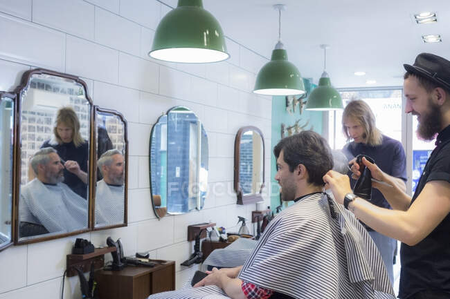 Hairdressers cutting customer's hair at barber shop — Stock Photo