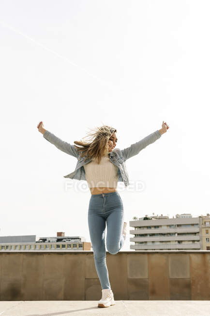 Studente universitario con le braccia tese ballare contro il cielo limpido nel campus — Foto stock