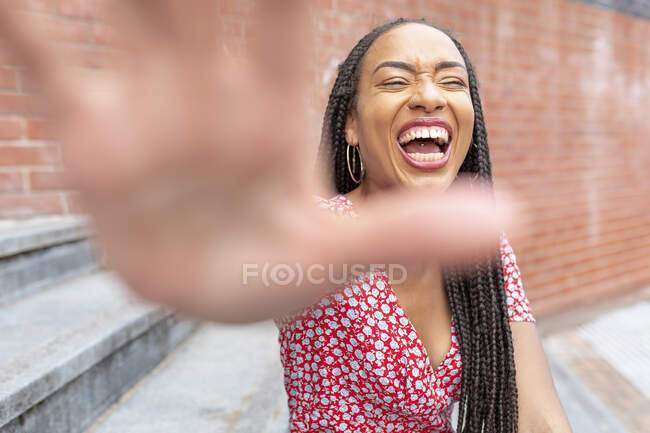 Женщина показывает стоп-жест, сидя на лестнице в городе — стоковое фото