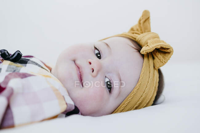 Sorridente bambina sdraiata sul letto a casa — Foto stock