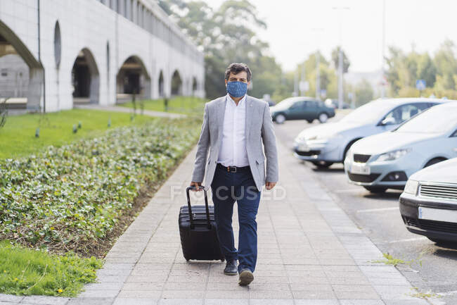 Чоловічий професійний ходьба з багажем на тротуарі під час COVID-19 — стокове фото