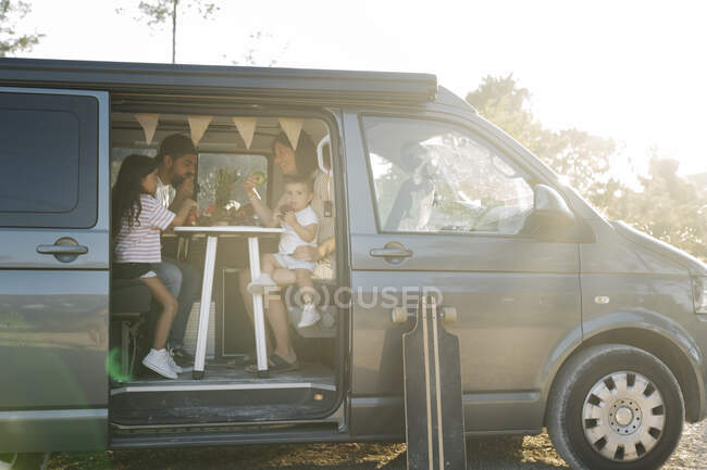 Familie isst bei Sonnenuntergang in Transporter im Park — Stockfoto
