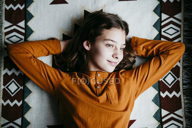 Lächelndes Mädchen schaut weg, während es zu Hause auf Decke liegt — Stockfoto