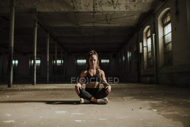 Atleta meditando mentre seduto in fabbrica abbandonata — Foto stock