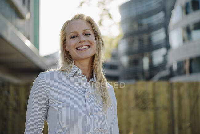 Mujer rubia sonriente empresaria en ropa de negocios en el distrito financiero - foto de stock