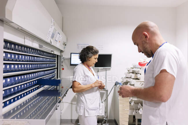 Farmacêuticos masculinos e femininos que trabalham na arrecadação do hospital — Fotografia de Stock
