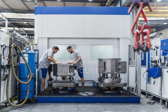 Professioneller männlicher Ingenieur begutachtet Maschine im Stehen in beleuchteter Fabrik — Stockfoto