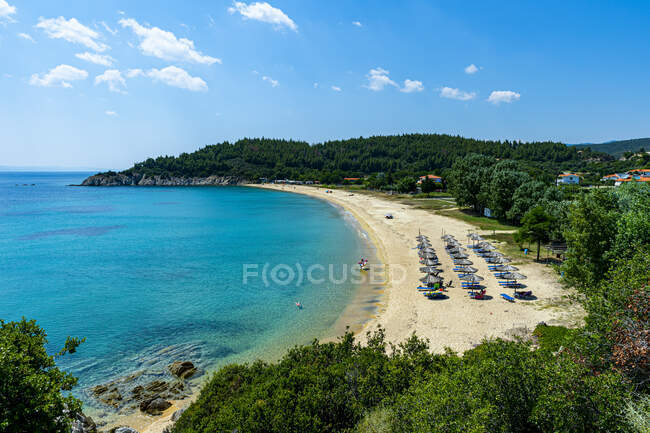 Greece, Sithonia, Umbrellas and deck chairs along sandy coastal beach in summer — Stock Photo