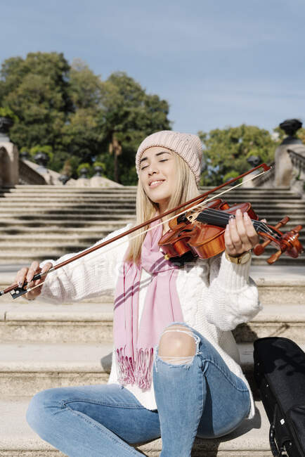 Giovane donna bionda che suona il violino seduta sulle scale — Foto stock