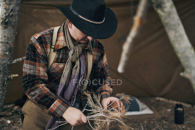 Bushcrafter usando sombrero mientras se prepara para la fogata - foto de stock