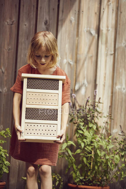 Девушка с отелем для насекомых, стоящая напротив дома во дворе — стоковое фото