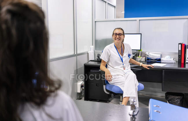 Farmacista sorridente che prende con il collega mentre lavora alla scrivania in ospedale — Foto stock