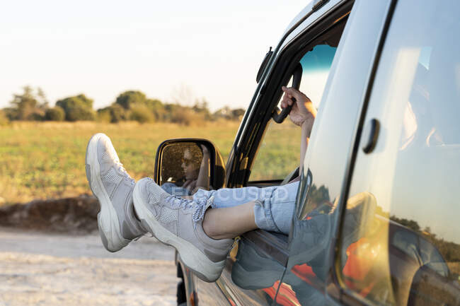 Ноги молодої жінки на вікні автомобіля під час заходу сонця — стокове фото