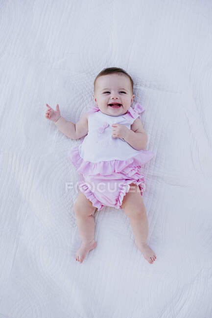 Sorridente bambina sdraiata sulla coperta bianca — Foto stock