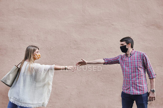 Casal mantendo distância social enquanto está de pé contra a parede — Fotografia de Stock