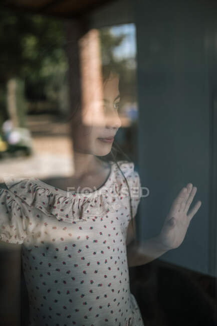 Menina olhando para longe visto através da janela de vidro — Fotografia de Stock