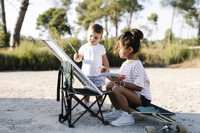 Dipinto bambina con sorella su tela al parco durante il tramonto — Foto stock