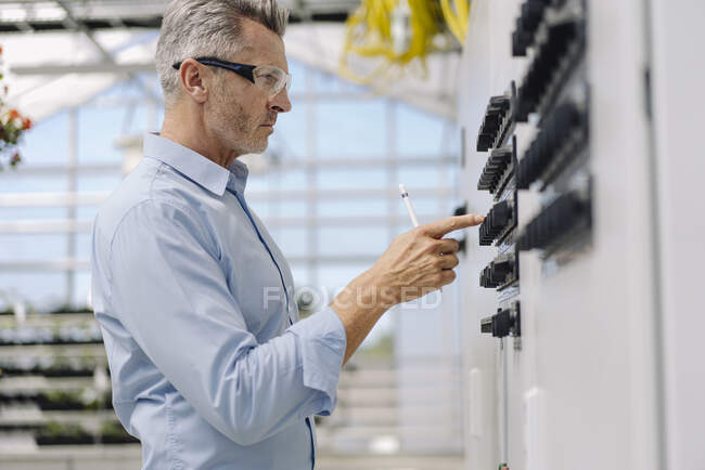 Чоловік професійний операційний контроль, стоячи в оранжереї. — стокове фото