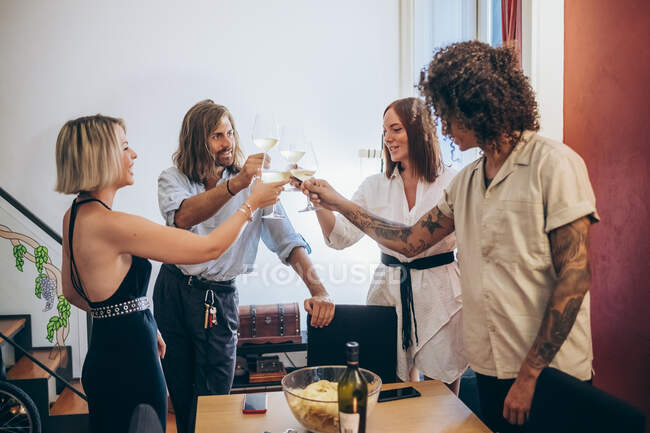 Друзья мужчины и женщины пьют бокалы во время вечеринки дома — стоковое фото