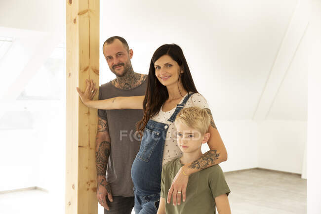 Pregnant woman with family standing against wall in new apartment — Stock Photo